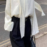 Løstsiddende bluse med polkaprikker og bånd, ideel til hverdagsbrug.