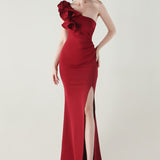 Asymmetrisk satin aftenkjole med flæser og blomster, pyntet med den ene skulder, med flæser og blomster.