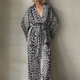 Et elegant todelt outfit bestående af en langærmet skjorte med tryk og bukser med vide ben og bælte