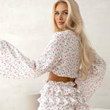 Todelt sæt bestående af en langærmet crop top med flæser, der bindes foran, og shorts med blomsterprint