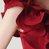 Asymmetrisk satin aftenkjole med flæser og blomster, pyntet med den ene skulder, med flæser og blomster.