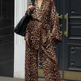 Et elegant todelt outfit bestående af en langærmet skjorte med tryk og bukser med vide ben og bælte