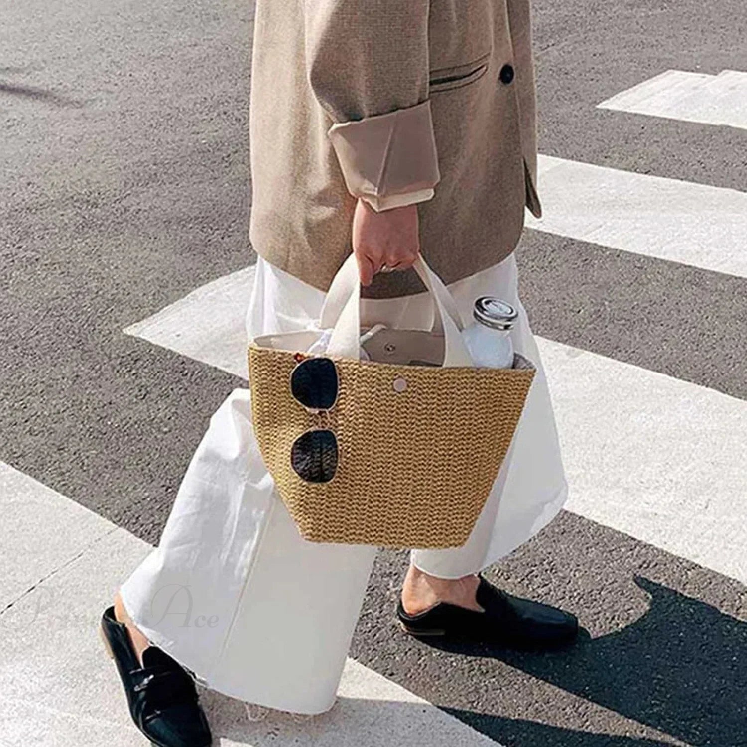 Elegant vævet stråhåndtaske i afslappet strandstil med hank foroven og skulderrem.